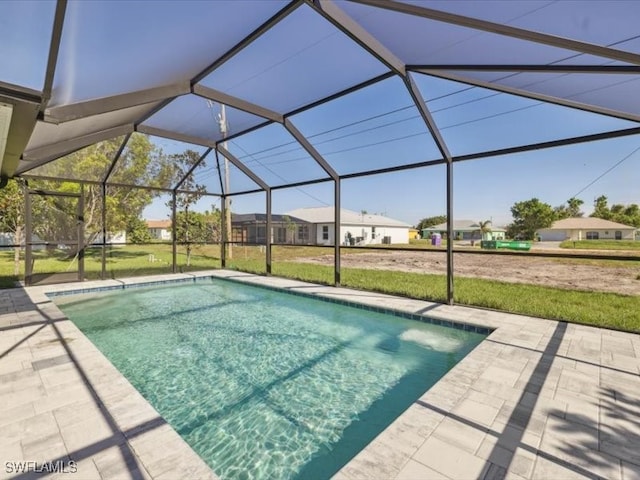 view of swimming pool featuring a lanai, a yard, and a patio