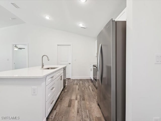 kitchen with lofted ceiling, a center island with sink, sink, appliances with stainless steel finishes, and white cabinetry