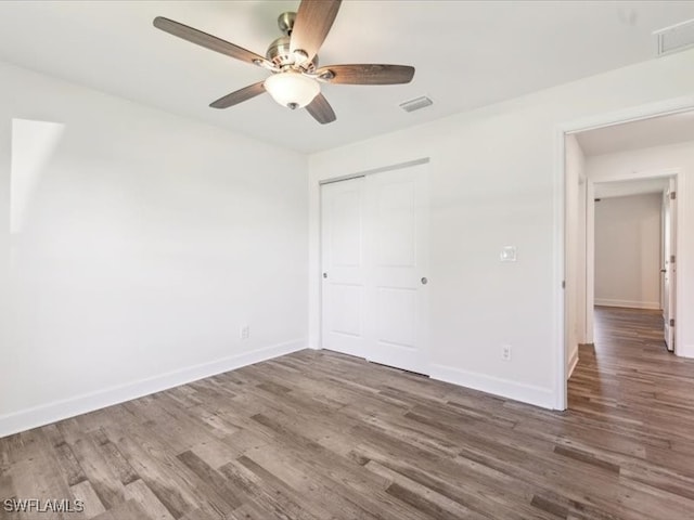 unfurnished bedroom featuring ceiling fan, a closet, and dark wood-type flooring