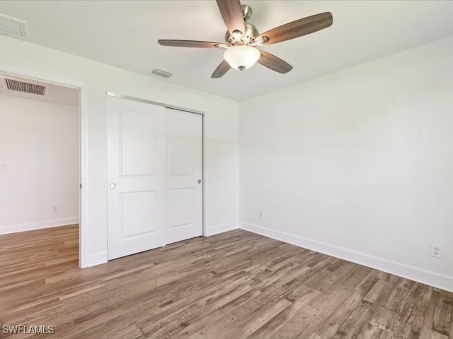 unfurnished bedroom featuring wood-type flooring, a closet, and ceiling fan