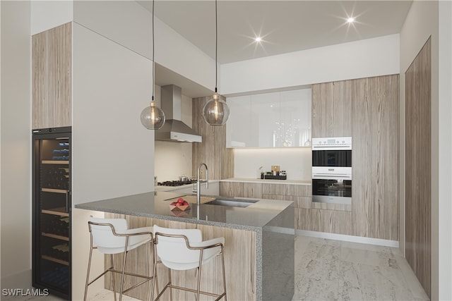 kitchen with white cabinetry, stainless steel appliances, hanging light fixtures, wall chimney range hood, and kitchen peninsula