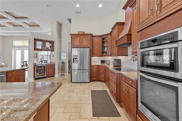 kitchen featuring custom exhaust hood, decorative backsplash, light stone countertops, appliances with stainless steel finishes, and beverage cooler