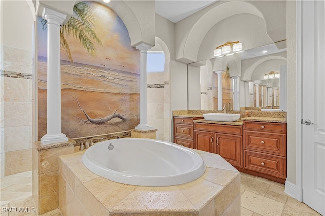 bathroom featuring tiled bath, vanity, and ornate columns