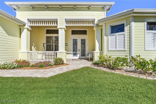 entrance to property with a porch, french doors, and a lawn