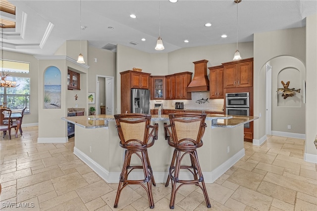 kitchen with premium range hood, light stone counters, stainless steel appliances, and a large island