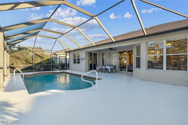 view of pool with glass enclosure, ceiling fan, and a patio area