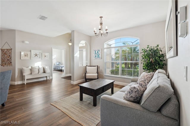 living room with dark wood-type flooring and a notable chandelier