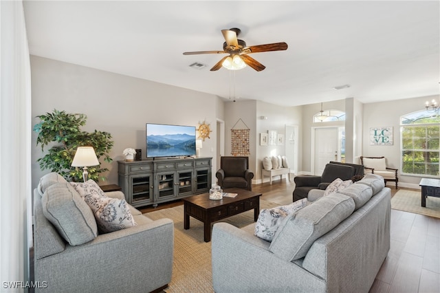 living room featuring ceiling fan with notable chandelier and light wood-type flooring