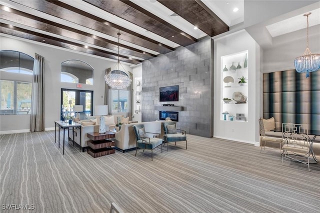 carpeted living room with beam ceiling, a large fireplace, a chandelier, and built in features