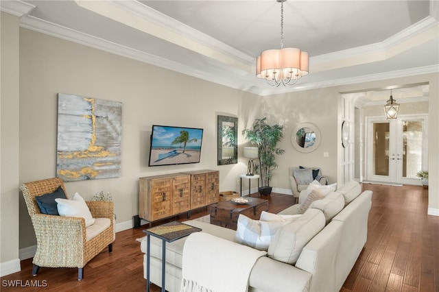 living room with french doors, an inviting chandelier, dark hardwood / wood-style flooring, crown molding, and a tray ceiling