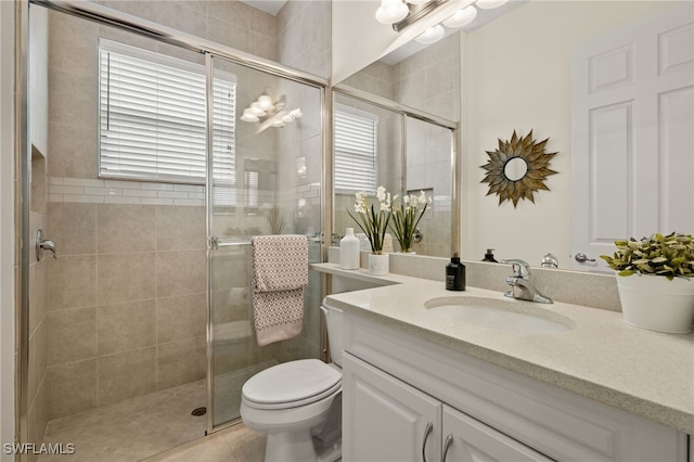 bathroom featuring tile patterned floors, vanity, toilet, and an enclosed shower