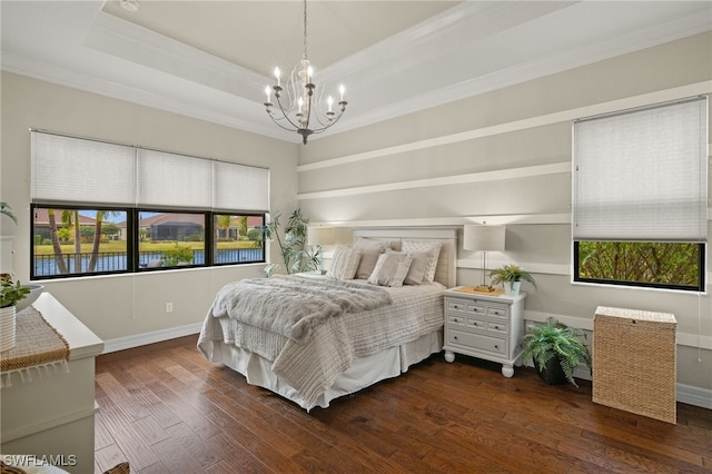 bedroom featuring dark hardwood / wood-style floors, a notable chandelier, crown molding, a tray ceiling, and a water view