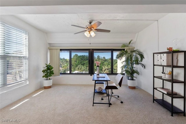 carpeted home office featuring vaulted ceiling, plenty of natural light, and ceiling fan