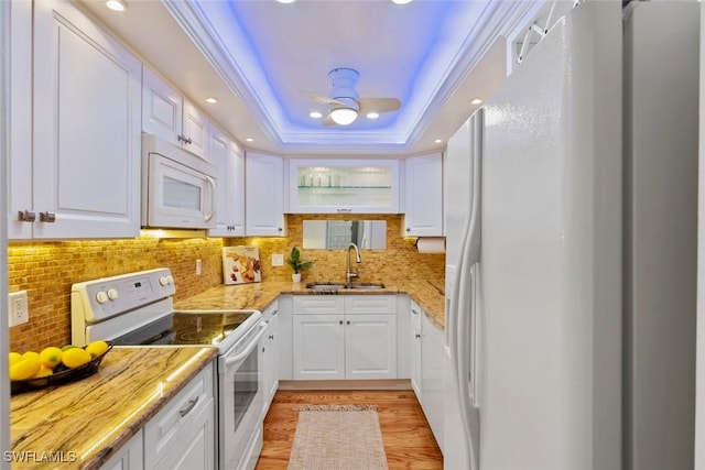 kitchen featuring white appliances, a raised ceiling, sink, light wood-type flooring, and white cabinetry