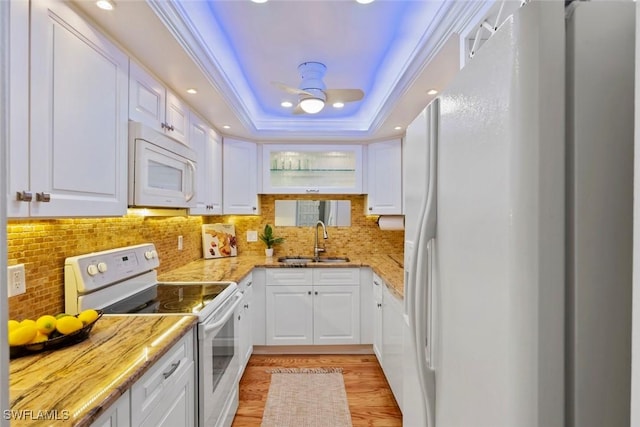 kitchen with a sink, white appliances, and white cabinets