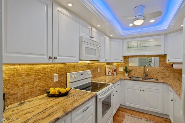 kitchen featuring a sink, a tray ceiling, white cabinetry, ceiling fan, and white appliances