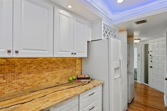kitchen with visible vents, white cabinetry, decorative backsplash, white refrigerator with ice dispenser, and light stone countertops