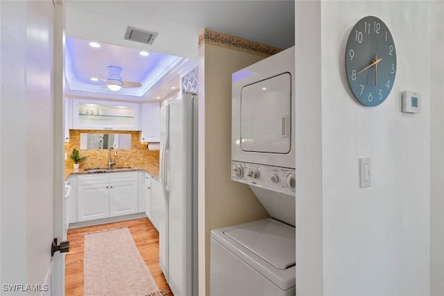 washroom with ceiling fan, crown molding, sink, light hardwood / wood-style flooring, and stacked washer and clothes dryer