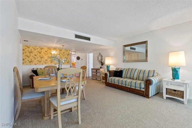 carpeted dining area with a textured ceiling, a notable chandelier, and visible vents