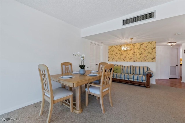 carpeted dining room with a textured ceiling and a chandelier