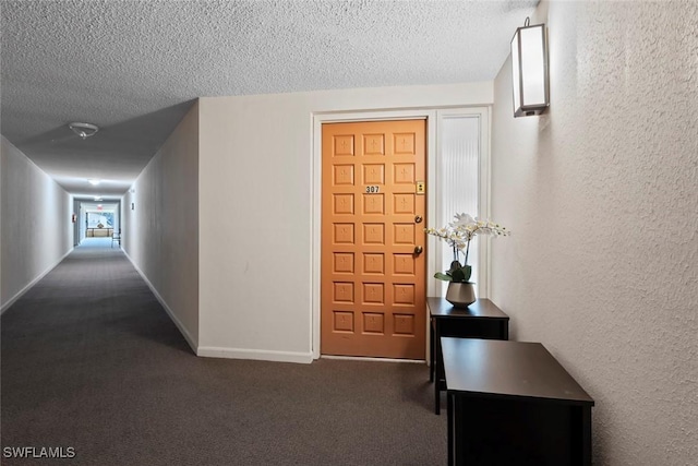 corridor with a textured ceiling, carpet, baseboards, and a textured wall