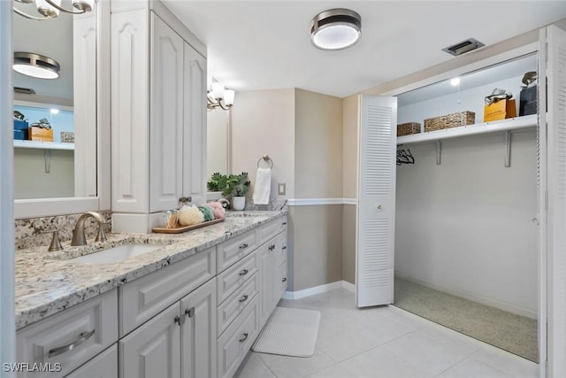 full bathroom featuring a sink, visible vents, tile patterned floors, double vanity, and baseboards