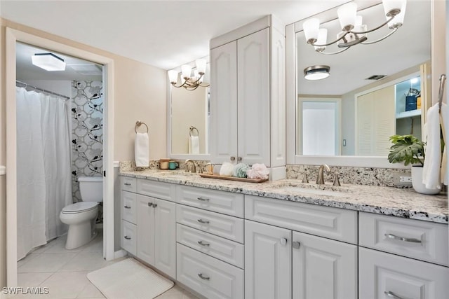 bathroom with tile patterned floors, vanity, an inviting chandelier, and toilet