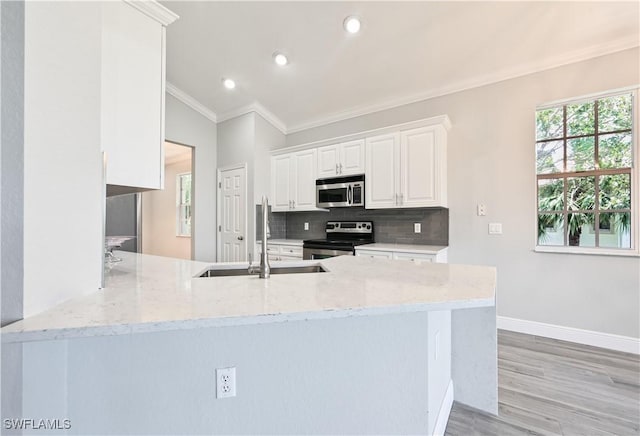 kitchen with white cabinetry, sink, stainless steel appliances, kitchen peninsula, and ornamental molding