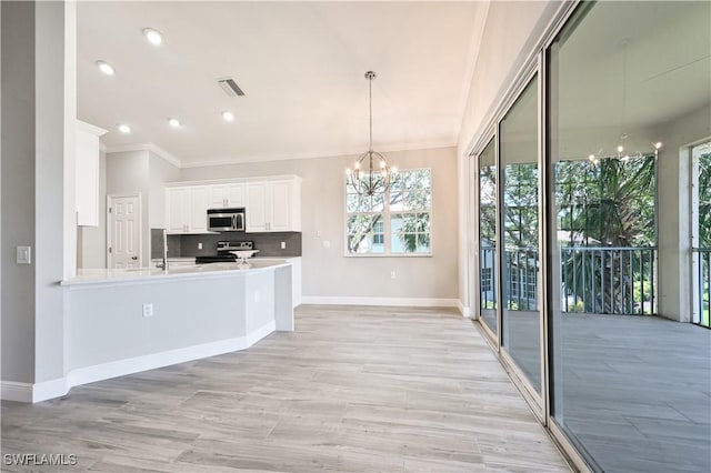 kitchen featuring appliances with stainless steel finishes, backsplash, decorative light fixtures, a notable chandelier, and white cabinetry