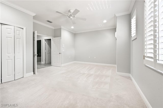 unfurnished bedroom with ceiling fan, light colored carpet, and crown molding