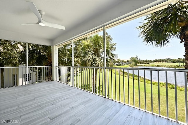 unfurnished sunroom featuring ceiling fan and a water view