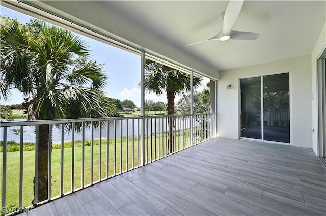 unfurnished sunroom featuring ceiling fan and a water view