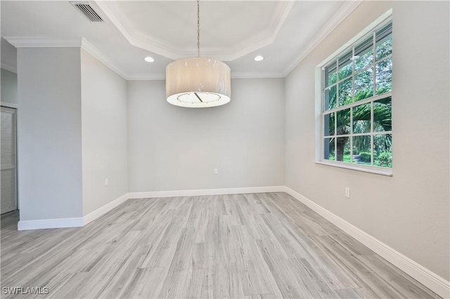 spare room featuring a tray ceiling, crown molding, and light hardwood / wood-style flooring