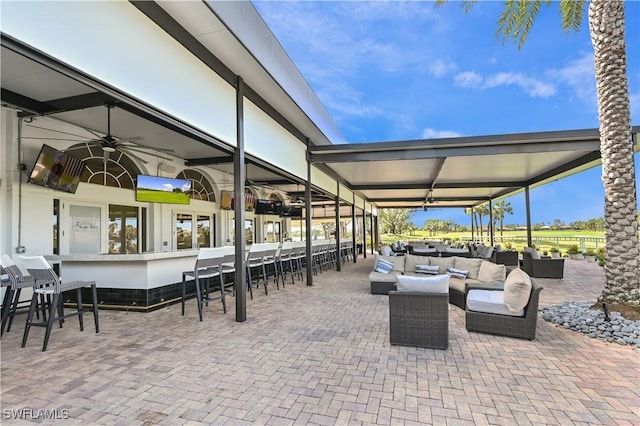 view of patio / terrace featuring exterior bar, an outdoor living space, and ceiling fan