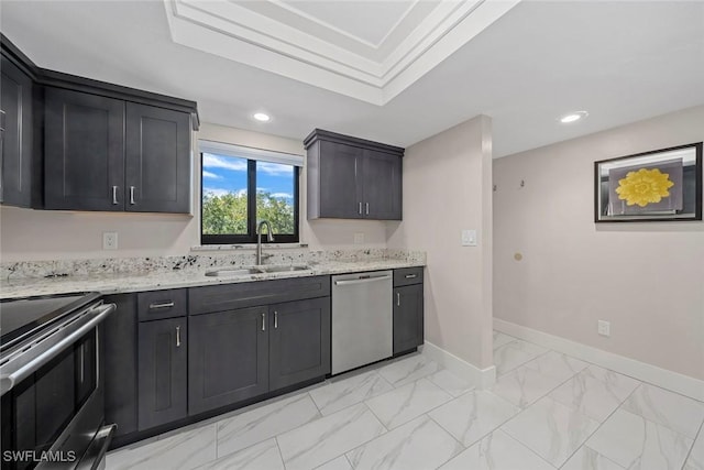 kitchen with light stone counters, appliances with stainless steel finishes, a raised ceiling, and sink