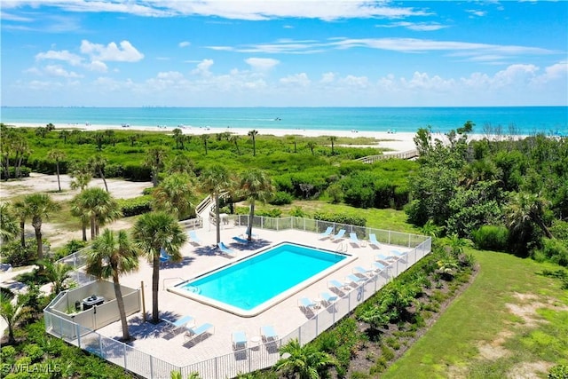 view of swimming pool featuring a view of the beach, a water view, and a patio area