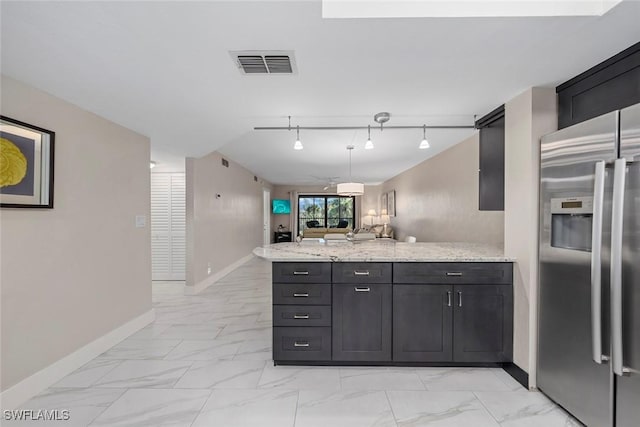 kitchen featuring rail lighting, light stone counters, stainless steel fridge with ice dispenser, kitchen peninsula, and pendant lighting