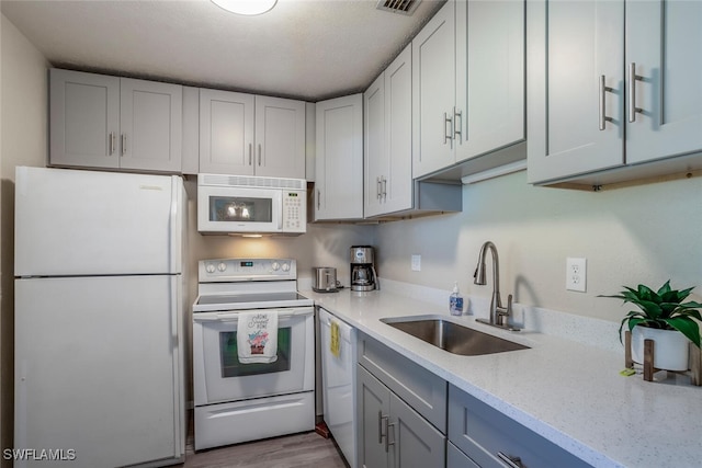 kitchen featuring light stone countertops, sink, white appliances, and light hardwood / wood-style flooring