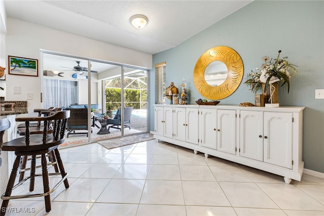 interior space featuring ceiling fan, light tile patterned flooring, and a textured ceiling