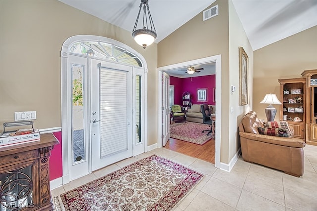 foyer entrance featuring ceiling fan, light tile patterned floors, and vaulted ceiling