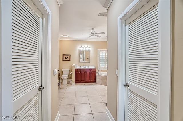 bathroom featuring vanity, crown molding, tile patterned flooring, toilet, and tiled bath