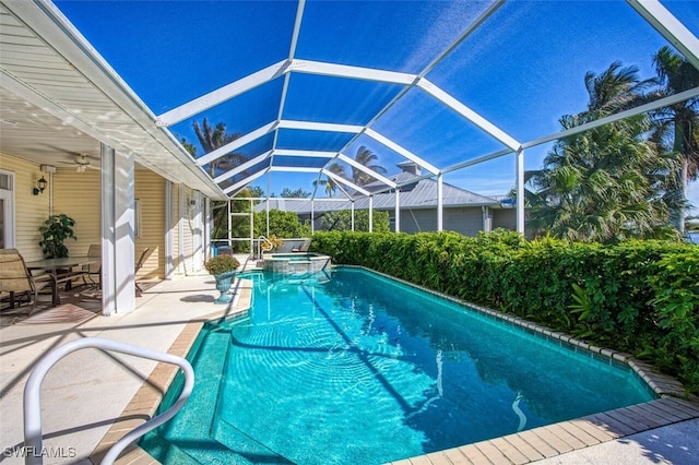 view of swimming pool with an in ground hot tub, glass enclosure, ceiling fan, and a patio area