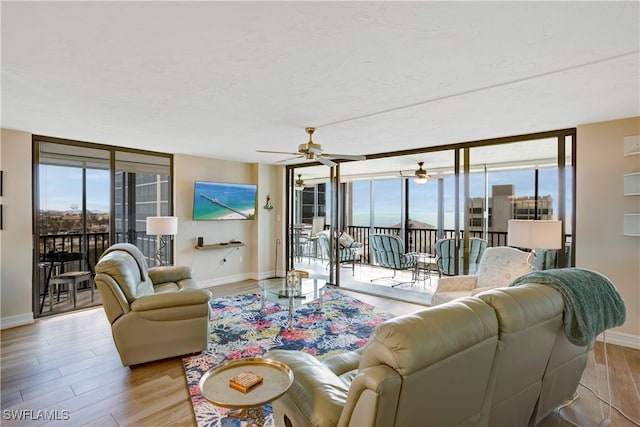 living room with light hardwood / wood-style floors, a wall of windows, and ceiling fan