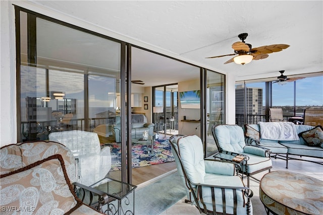 living room with ceiling fan, a wall of windows, and light wood-type flooring