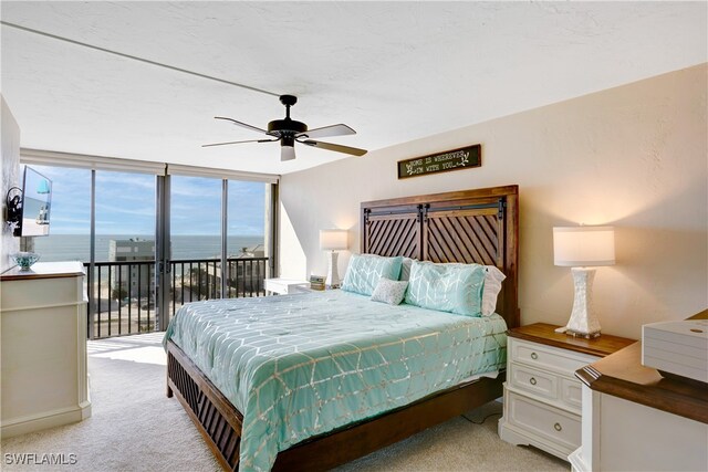 bedroom with ceiling fan, a water view, light carpet, and access to outside