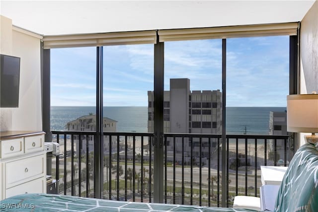 bedroom with multiple windows, a water view, and a wall of windows