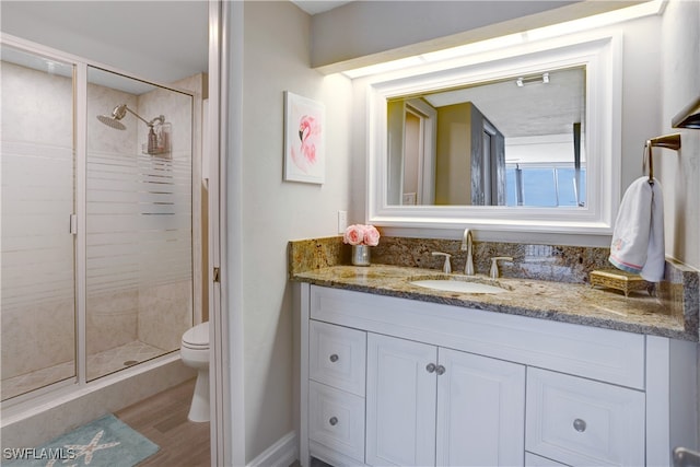 bathroom featuring hardwood / wood-style flooring, vanity, toilet, and a shower with shower door