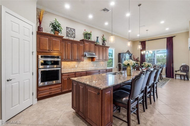 kitchen featuring pendant lighting, crown molding, sink, double oven, and a large island