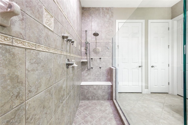 bathroom featuring tile patterned floors, a shower with shower door, and tile walls