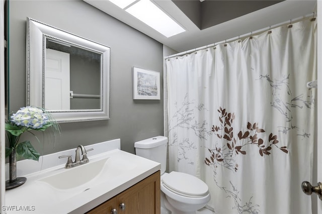 bathroom featuring a skylight, vanity, a shower with shower curtain, and toilet